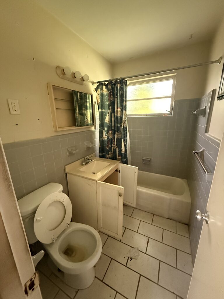 Outdated bathroom with a worn vanity, older tile and tub